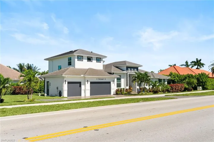 View of front of house with stucco siding, a garage, a front yard, and driveway