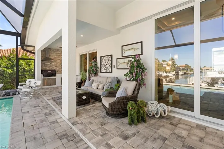 View of patio with glass enclosure, an outdoor pool, a sunroom, a water view, and a grill