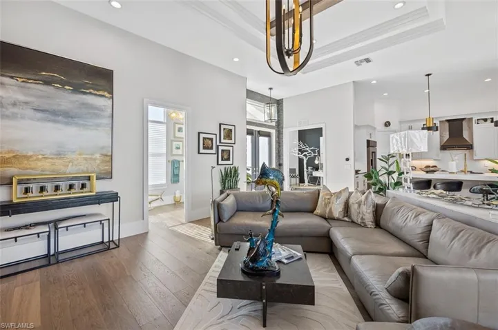 Living area featuring recessed lighting, a raised ceiling, hardwood / wood-style flooring, and crown molding