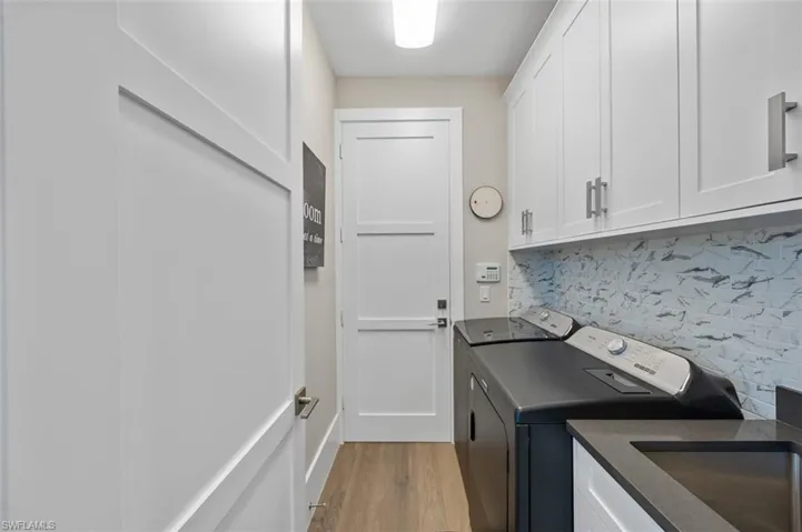 Laundry area featuring light wood-style floors, washer and dryer, and cabinet space