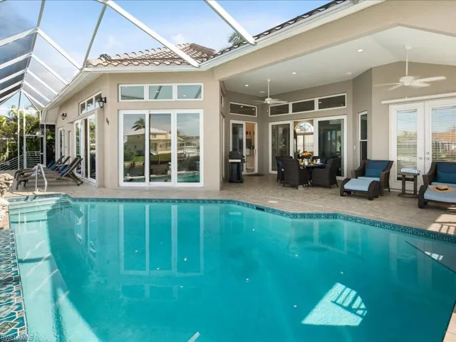 Outdoor pool featuring a sunroom, ceiling fan, a patio area, a lanai, and grilling area