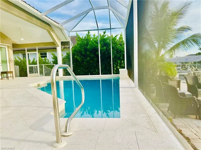 Outdoor pool with a sunroom, a patio area, glass enclosure, and ceiling fan