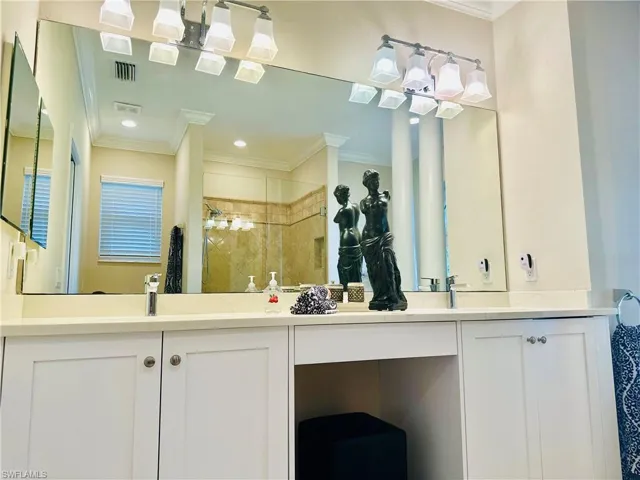 Bathroom with a stall shower, double vanity, and ornamental molding