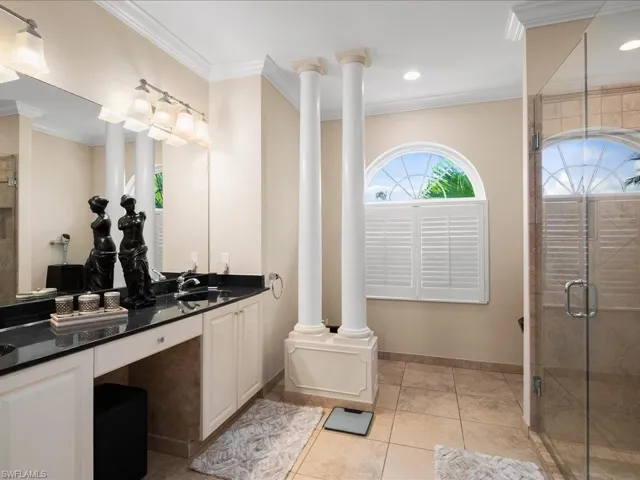Full bath with ornamental molding, double vanity, a shower stall, and light tile patterned floors