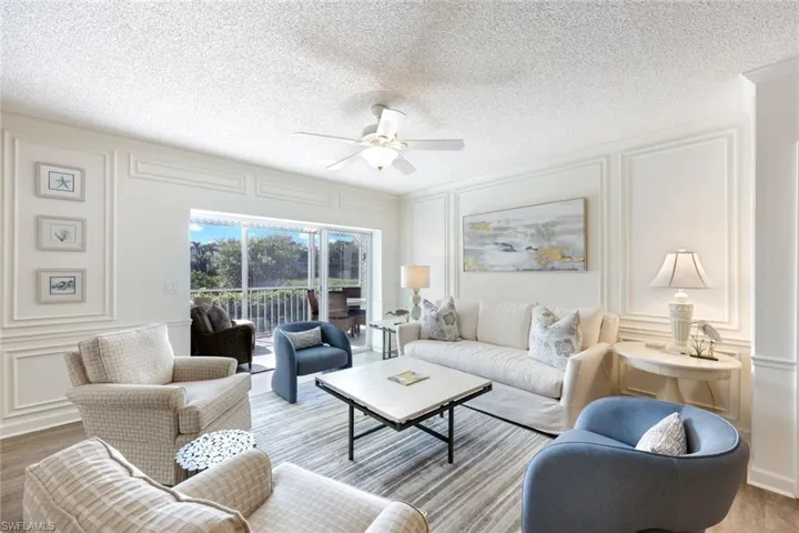 Living area with a decorative wall, a ceiling fan, wood finished floors, and a textured ceiling