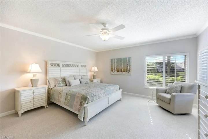 Bedroom featuring ornamental molding, carpet flooring, a textured ceiling, and ceiling fan