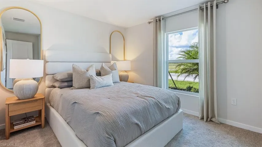 Model home. Bedroom featuring baseboards and light colored carpet