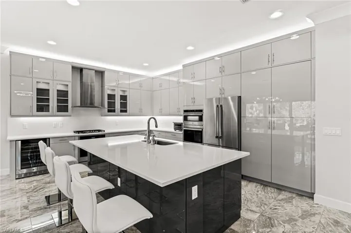 Sleek Euro cabinetry, extended upper cabinets, natural gas cooktop with stainless steel vent hood, a Thermador refrigerator, dual ovens, quartz counters and backsplash, plus wine fridge.