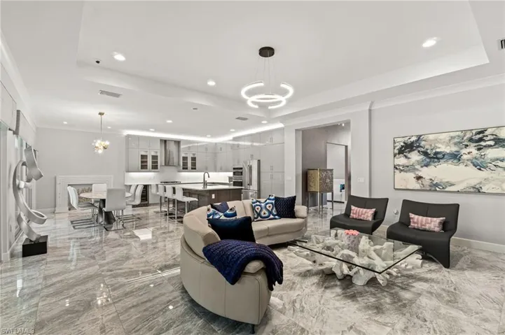 Elegant, open-concept living and dining space with designer lighting, custom finishes, including the custom fireplace facade in the dining area.