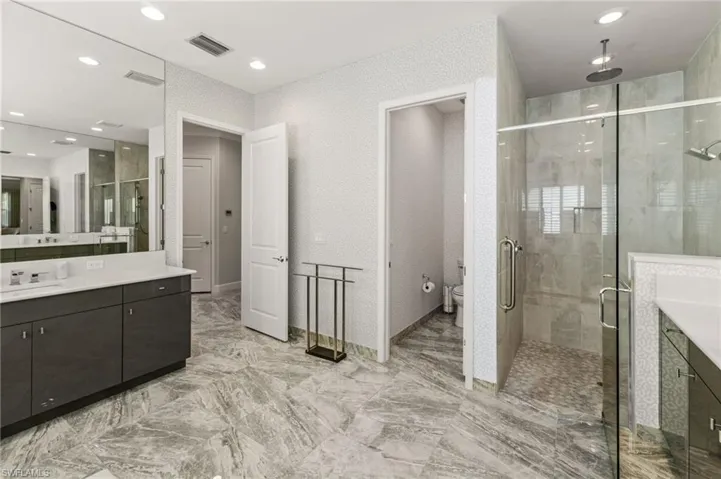 Primary suite bathroom with dual vanities, large walk in shower, water closet.