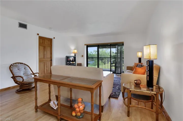 Living area with light wood-style floors, baseboards, and visible vents