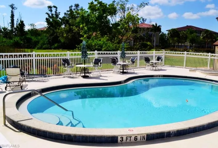 Community pool featuring a patio area and fence