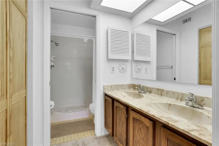 Full bathroom with toilet, a skylight, visible vents, and a sink