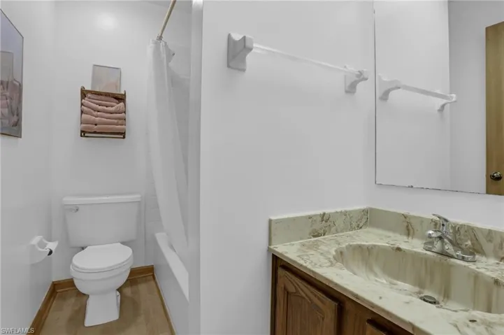 Full bath with toilet, shower / tub combo, baseboards, and vanity