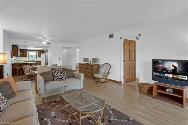 Living room featuring ceiling fan, light wood finished floors, visible vents, and baseboards