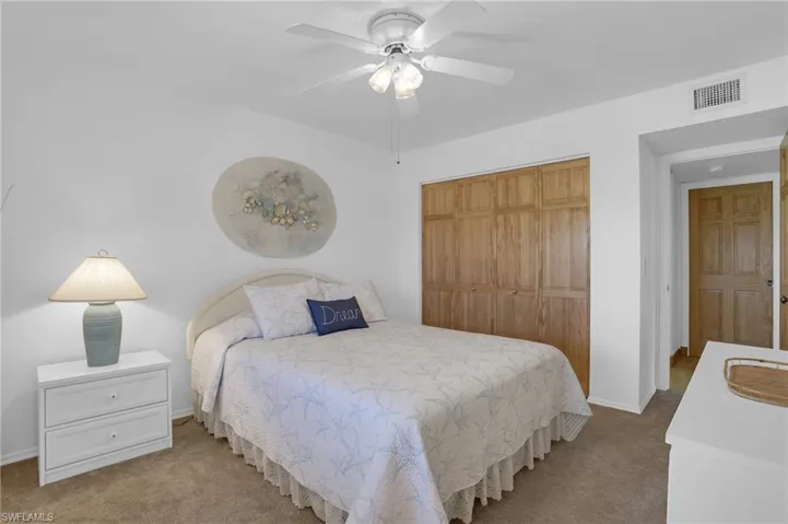 Carpeted bedroom featuring a ceiling fan, baseboards, visible vents, and a closet