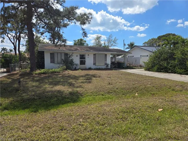 Ranch-style home with concrete driveway, stucco siding, fence, a front yard, and a carport
