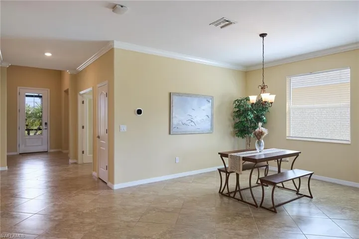 Dining area with crown molding, light tile patterned floors, and an inviting chandelier