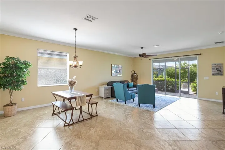 Tiled dining area with ornamental molding and ceiling fan with notable chandelier