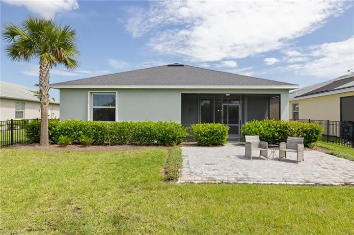Back of property featuring a patio, a sunroom, and a lawn