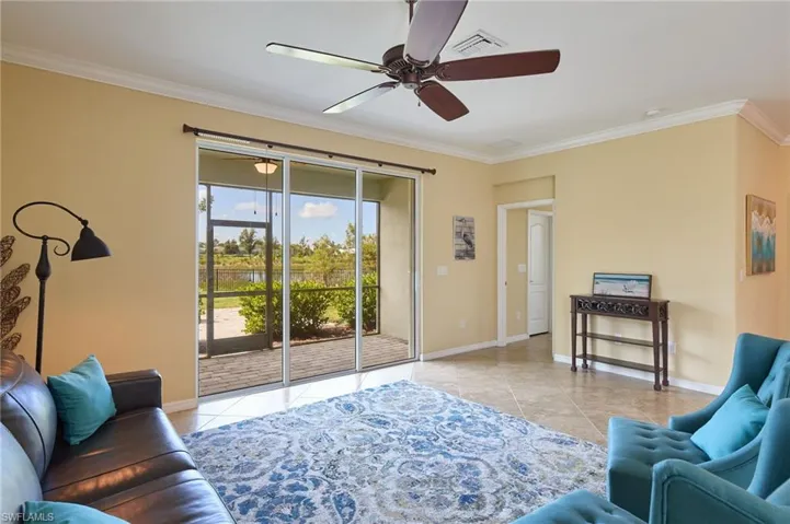 Tiled living room featuring ceiling fan and crown molding