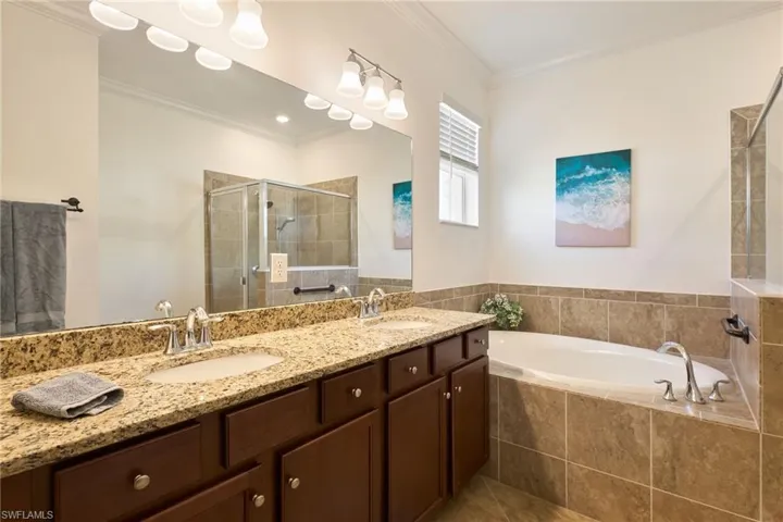 Bathroom featuring ornamental molding, shower with separate bathtub, tile patterned floors, and double vanity