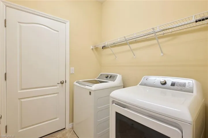 Laundry area with light tile patterned flooring and separate washer and dryer