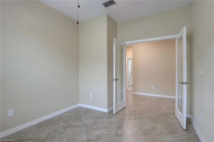 Empty room with french doors and light tile patterned floors