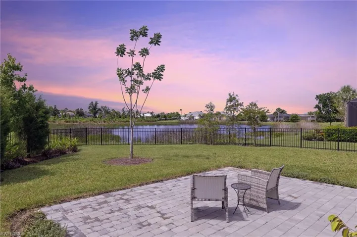 Patio terrace at dusk with a water view and a yard