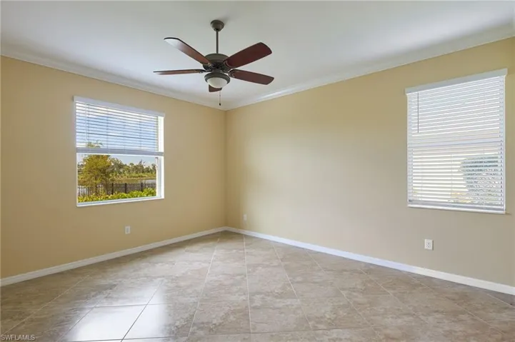 Tiled spare room featuring ornamental molding, a wealth of natural light, and ceiling fan