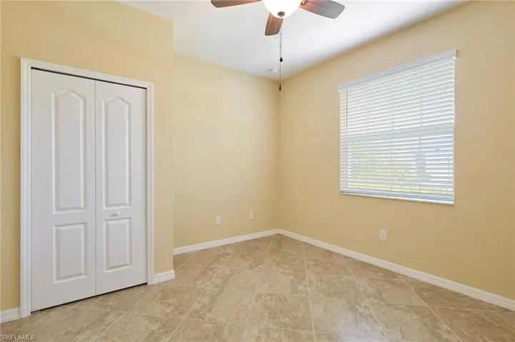Unfurnished bedroom featuring a closet, light tile patterned floors, and ceiling fan
