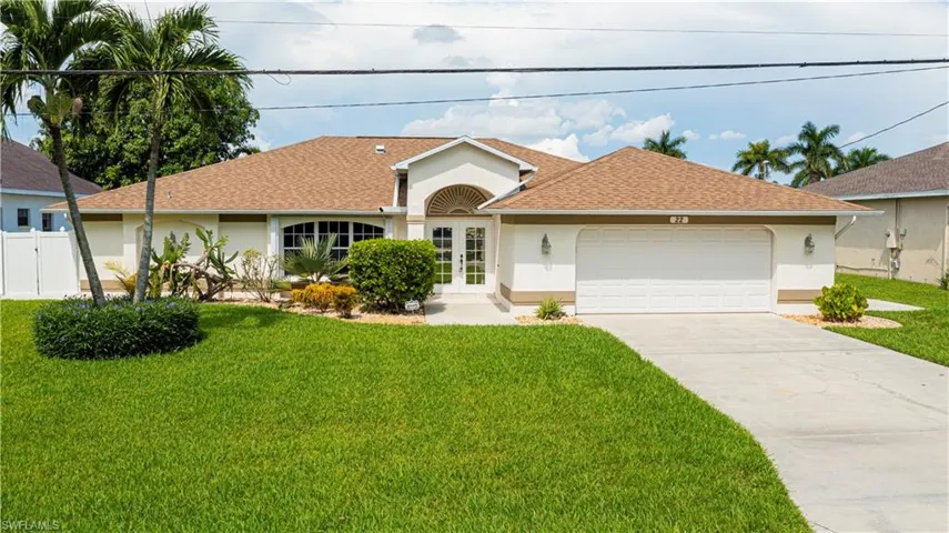 White stucco exterior with a brown shingle roof, arched entry, two-car garage, and a concrete driveway