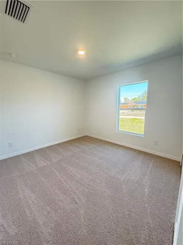 Spare room featuring light colored carpet and baseboards