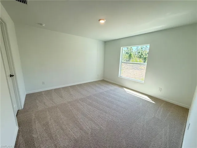 Unfurnished bedroom with light colored carpet and baseboards