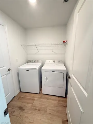 Laundry room with washing machine and dryer and wood finish floors