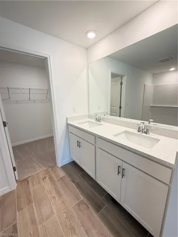 Bathroom featuring double vanity, a walk in closet, wood tiled floors, and recessed lighting
