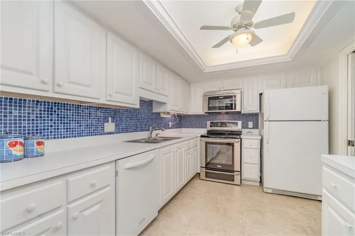 Kitchen view from LV RM includes a tray ceiling, stainless steel stove and microwave, and lots of storage space