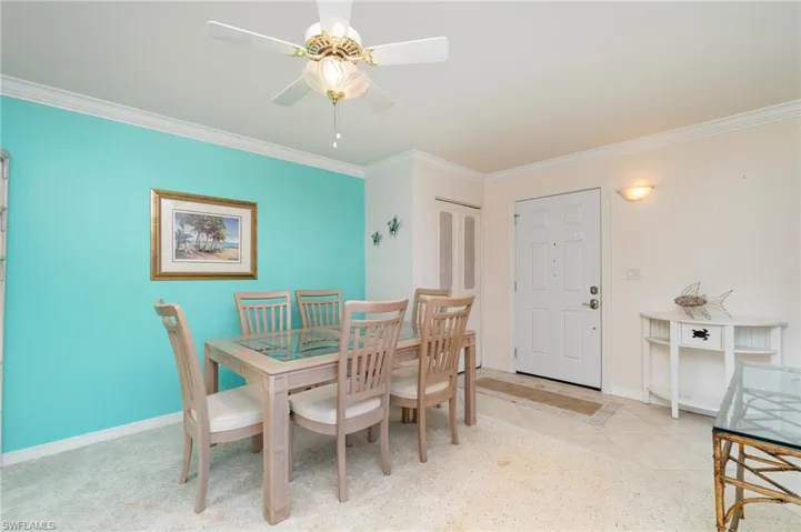Dining space featuring crown molding, entry with light tile patterned floors, closet and ceiling fan