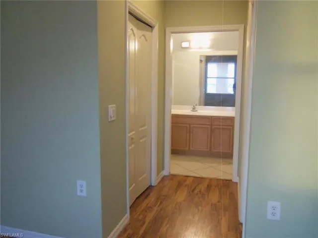 Hall featuring dark wood-style flooring and baseboards