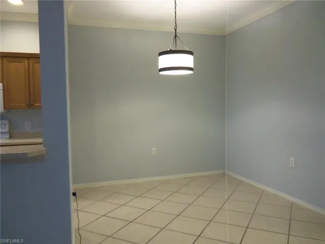 Unfurnished dining area with crown molding and light tile patterned flooring