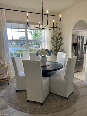 Dining space with arched walkways, a chandelier, and wood finished floors
