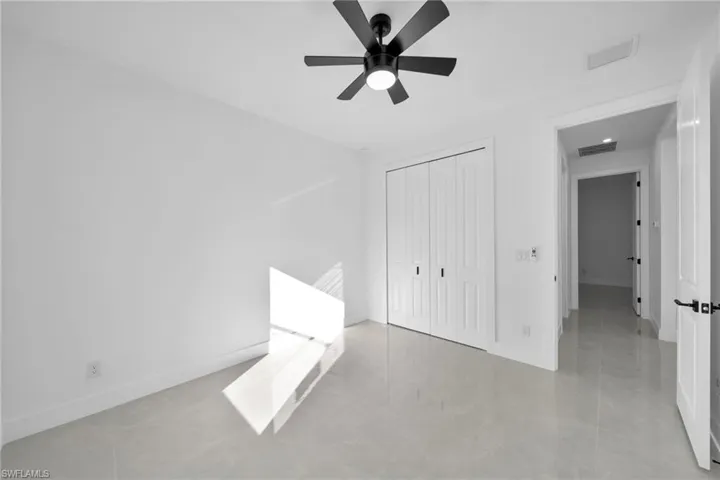 Unfurnished bedroom featuring a closet, light tile patterned floors, and a ceiling fan