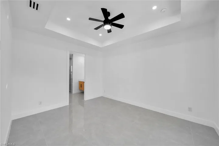 Spare room with a tray ceiling, recessed lighting, a ceiling fan, and light tile patterned floors