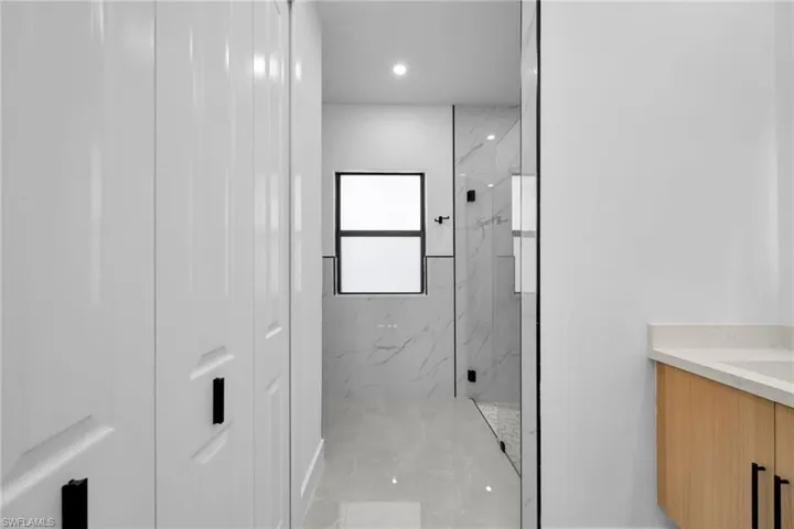 Bathroom featuring a marble finish shower, vanity, and recessed lighting