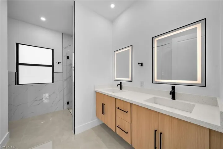 Full bath featuring double vanity, a marble finish shower, recessed lighting, and light tile patterned floors