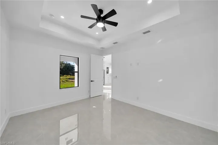Spare room featuring a raised ceiling, recessed lighting, a ceiling fan, and light tile patterned floors