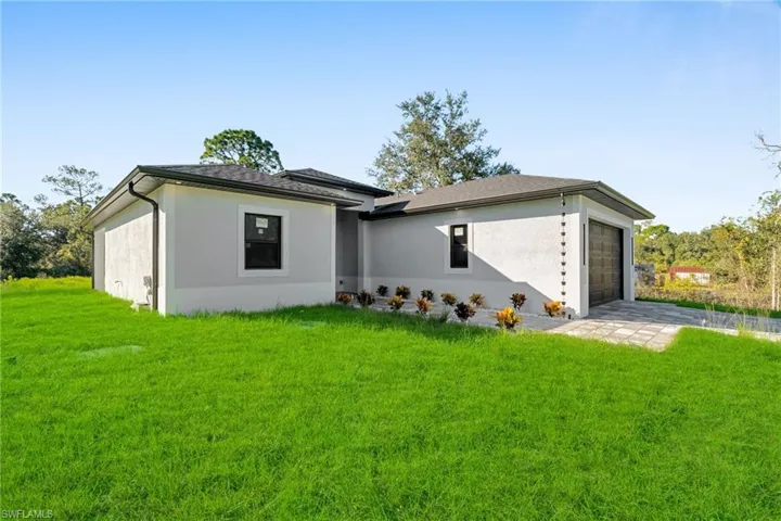 View of front of house with a front lawn, a garage, stucco siding, and driveway