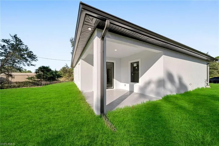 Rear view of house featuring stucco siding, a lawn, and a patio