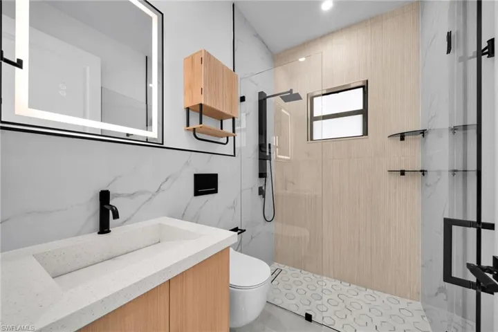 Full bathroom featuring a marble finish shower, vanity, and tile walls
