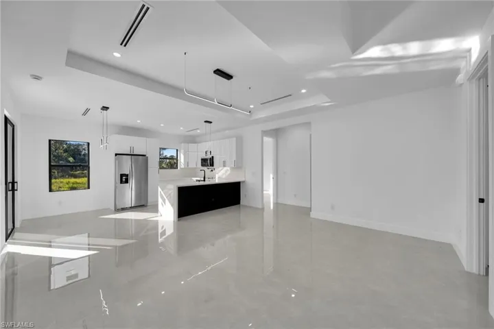 Unfurnished living room with a raised ceiling and recessed lighting